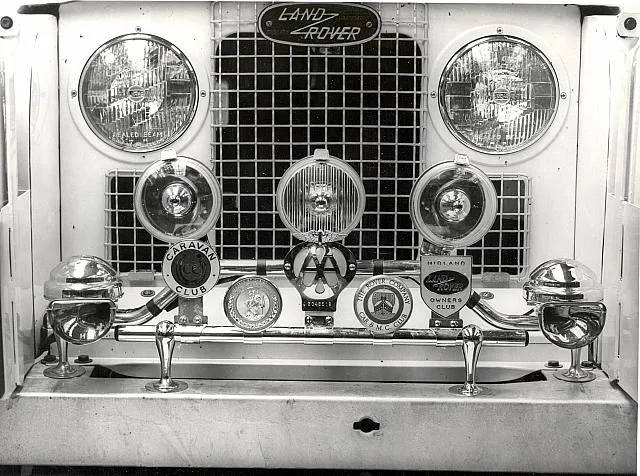 A collection of club badges on a Land Rover grille
