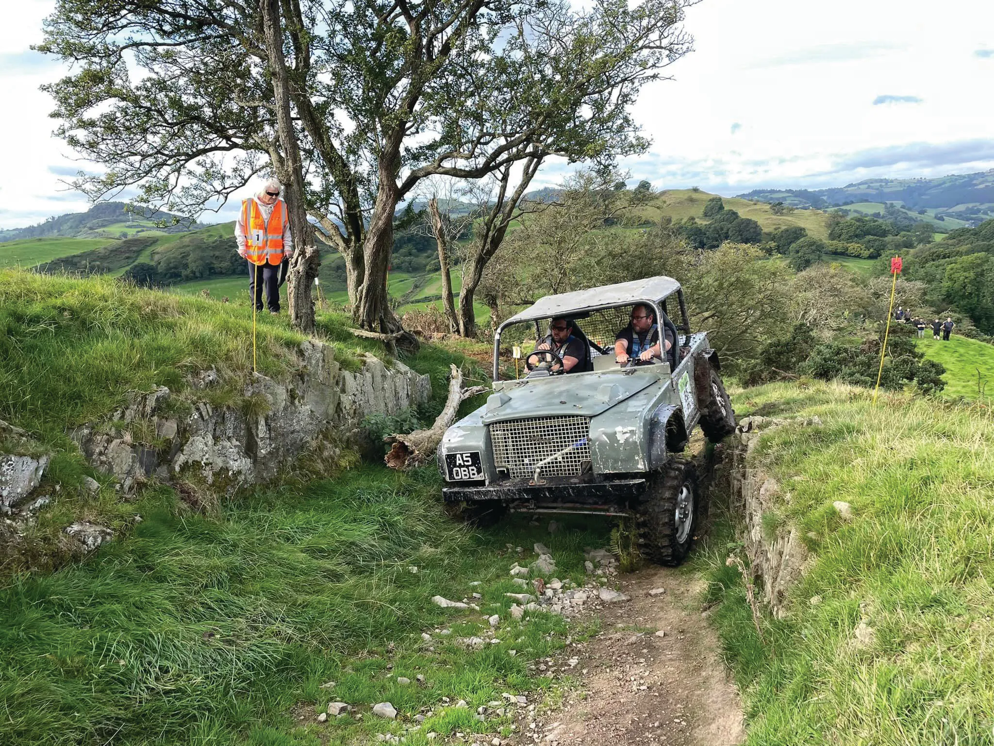 A cross-country vehicle tackling a steep wooded section